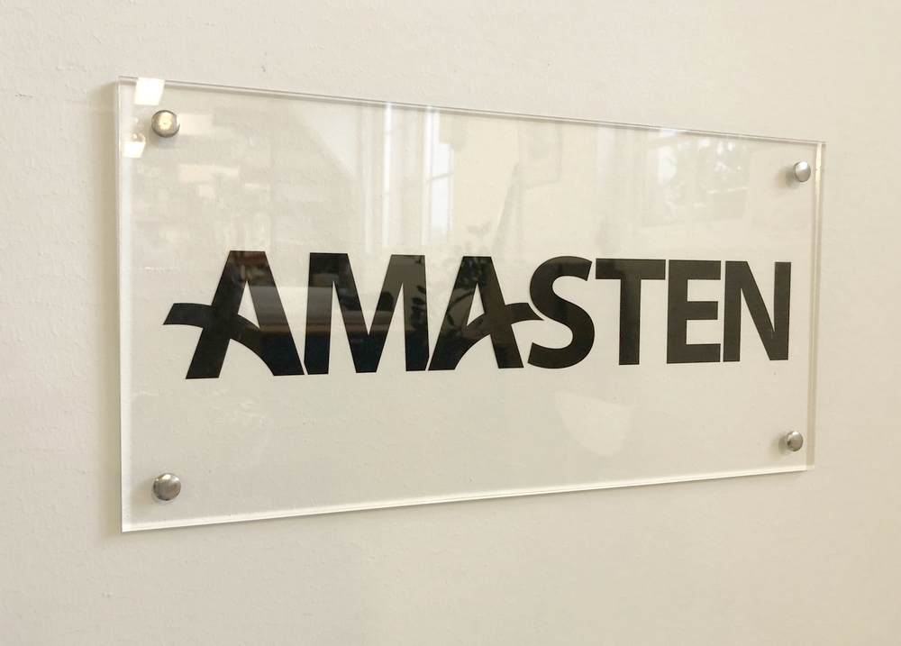 En transparent väggskylt med texten AMASTEN